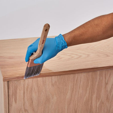 Minwax Water Based Pre-Stain Wood Conditioner being applied to a piece of furniture with a brush.