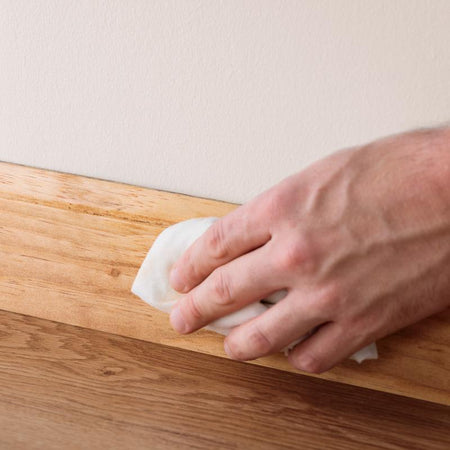 Wiping away excess Minwax Wood Putty from a baseboard.