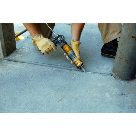 Quikrete Gray Polymer Concrete Self-Leveling Sealant being applied to a gap in sidewalk.