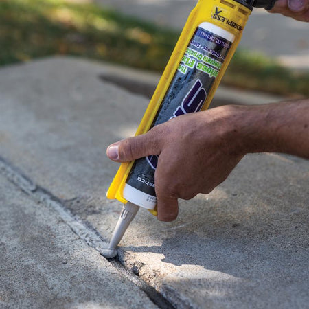 Sashco 10.5 Oz Gray Slab Concrete Repair Sealant 16210 being applied to a crack in concrete.