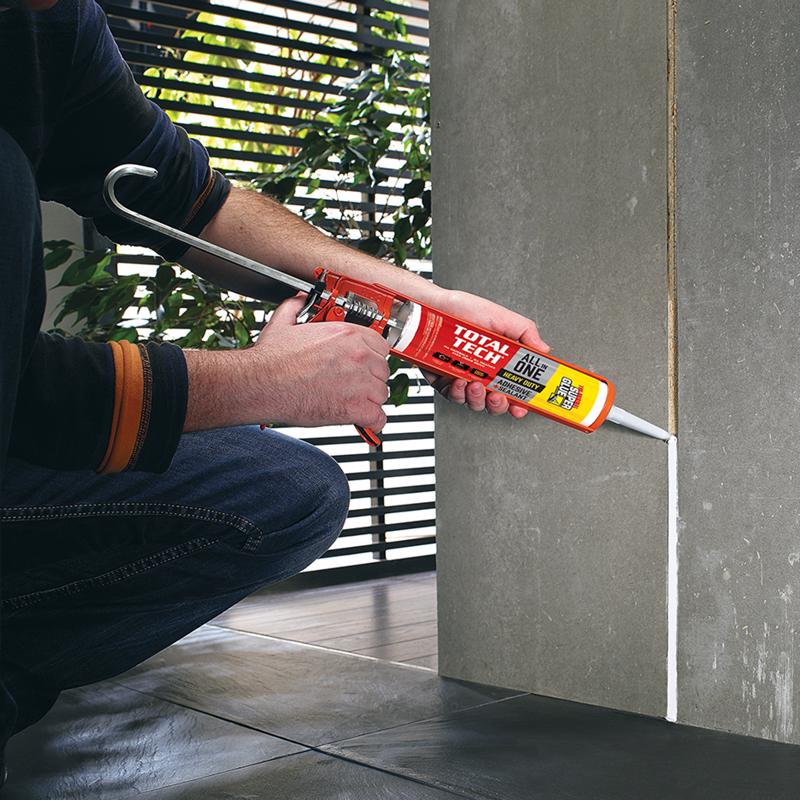 The Original Super Glue Total Tech Construction Adhesive Sealant being applied to a gap in tile on a wall.