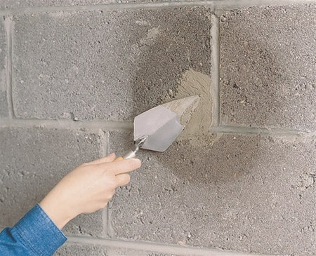 UGL Drylok Fast Plug Hydraulic Cement being applied to a concrete block wall.