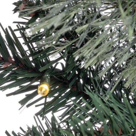 Close-up of a Christmas wreath with a single light bulb embedded in the branches.