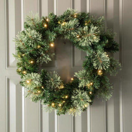 Decorative green Christmas wreath with lights on a door