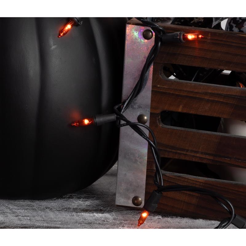 Close-up of a metal object with glowing orange Halloween lights on a dark background