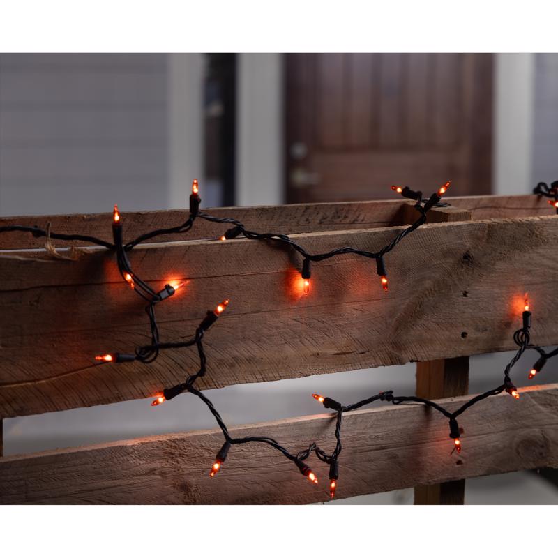 Orange halloween string lights on a wooden surface with a blurred background