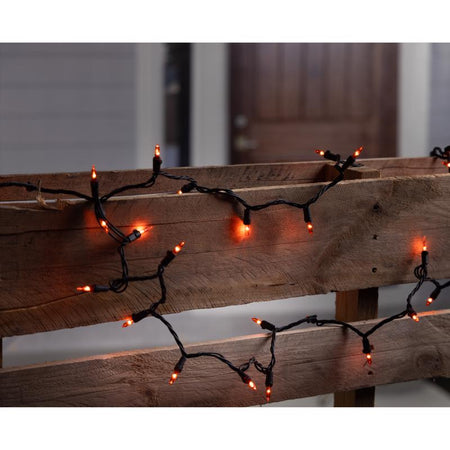Orange halloween string lights on a wooden surface with a blurred background