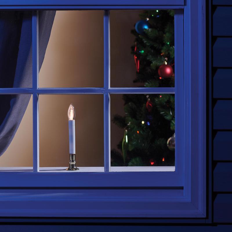 Flameless candle on a windowsill with a Christmas tree inside