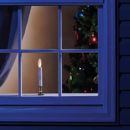 Flameless candle on a windowsill with a Christmas tree inside