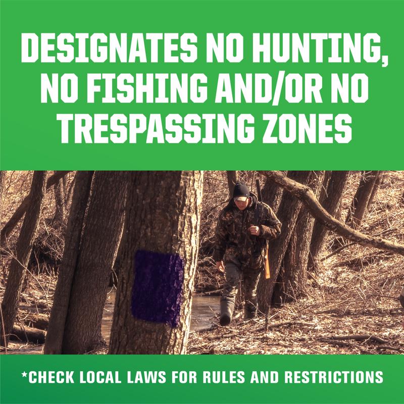 Person in camouflage walking through a forest with a green warning sign about hunting, fishing, and trespassing regulations.