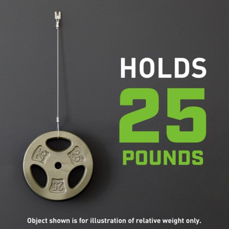 Weight plate with a 3M CLAW drywall picture hanger labeled 'Holds 25 Pounds' on a dark background