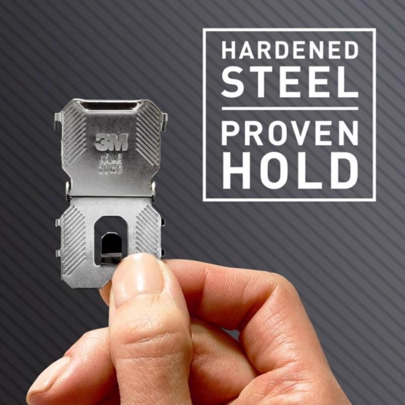 Hand holding a 3M CLAW drywall picture hanger against a gray background with text 'Hardened Steel Proven Hold'.