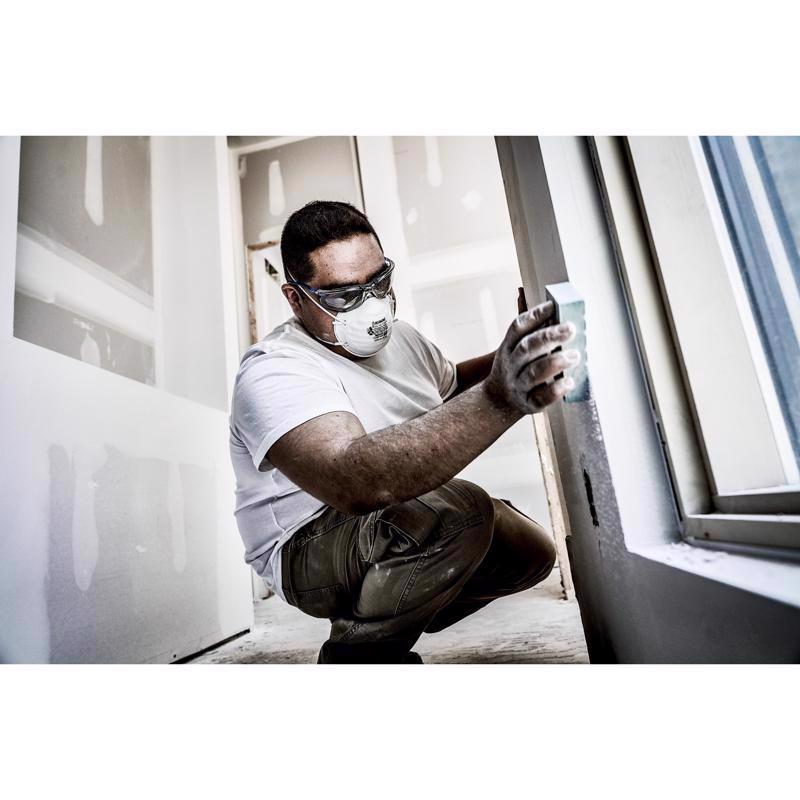 Person installing a window with protective gear in a room.