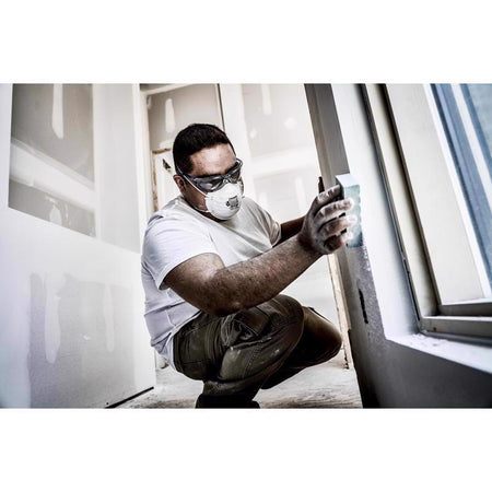 Person installing a window with protective gear in a room.