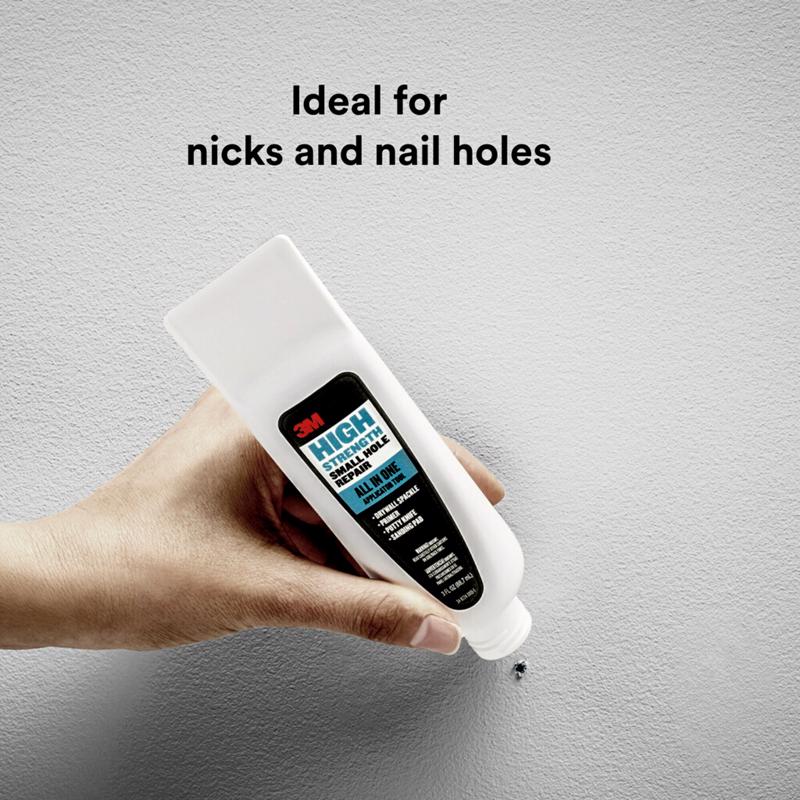 3M High Strength Small Hole Repair All-In-One Application Tool being applied to a nail hole on a wall.