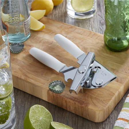 Swing-A-Way White Steel Manual Can Opener 407WH on a wooden cutting board with lemons, limes, and drinks in the background.