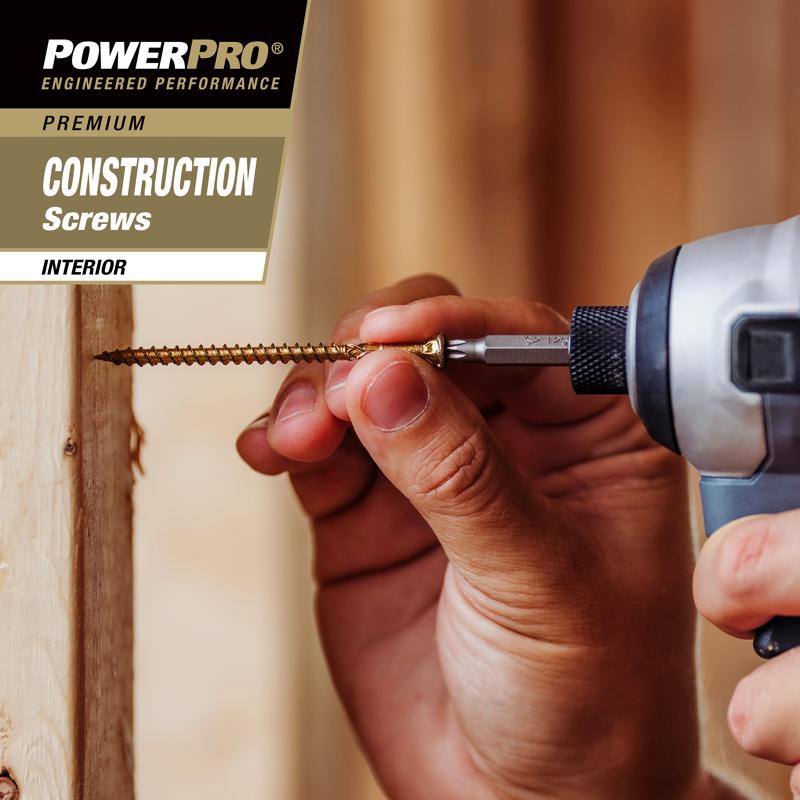 Hand using a drill bit with PowerPro screws on a wooden surface
