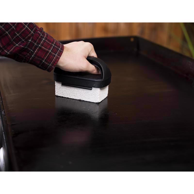 Man using the scrubbing block of the Blackstone 8-Pc Culinary Grill Cleaning Kit 5463 on a grill