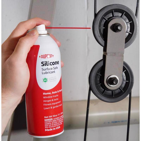 Hand holding a can of Dupont silicone lubricant near a window track.