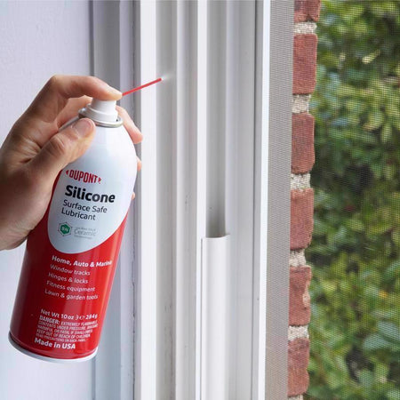 Person using a DuPont silicone lubricant can on window tracks.