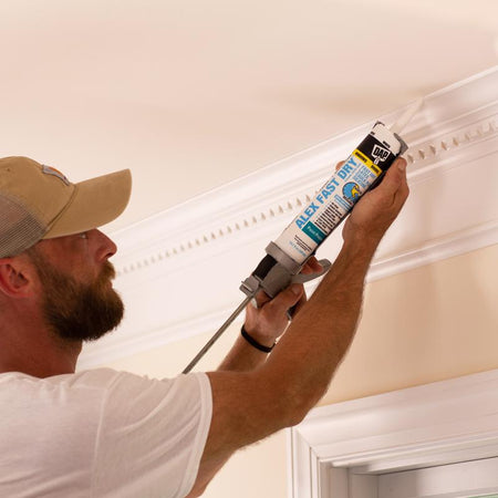 DAP Alex Fast Dry Acrylic Latex Caulk White being applied by a man to crown molding.