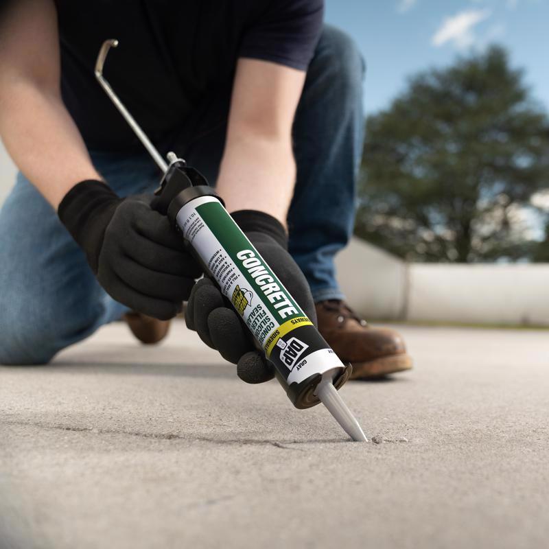 Man applying DAP 10.3 Oz Gray Watertight Concrete Filler & Sealant to a crack in concrete.