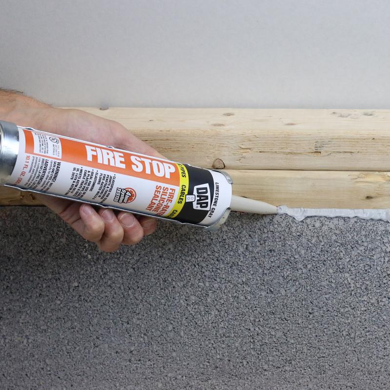 DAP 10 Oz Limestone Fire Stop Fire Rated Silicone Sealant being applied at gap between concrete and wood.