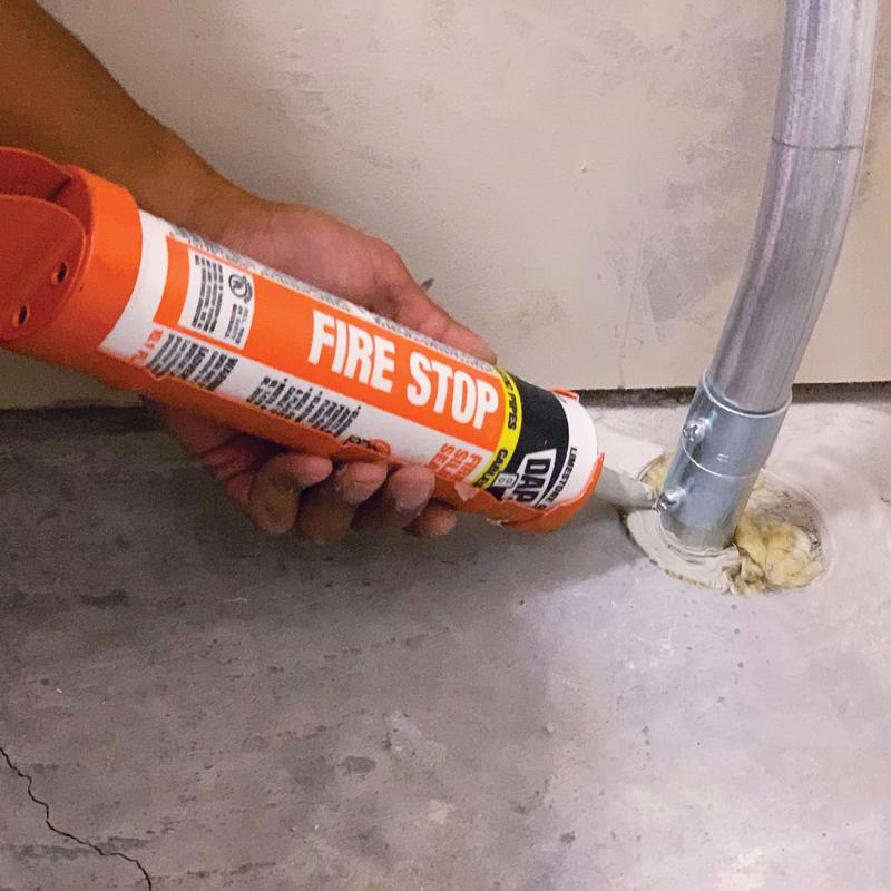 DAP 10 Oz Limestone Fire Stop Fire Rated Silicone Sealant being applied at metal tubing on floor.