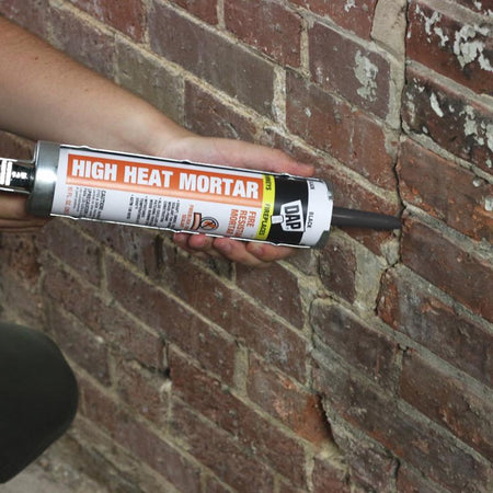 DAP 10 Oz Black High Heat Mortar being applied to crack in brick wall.
