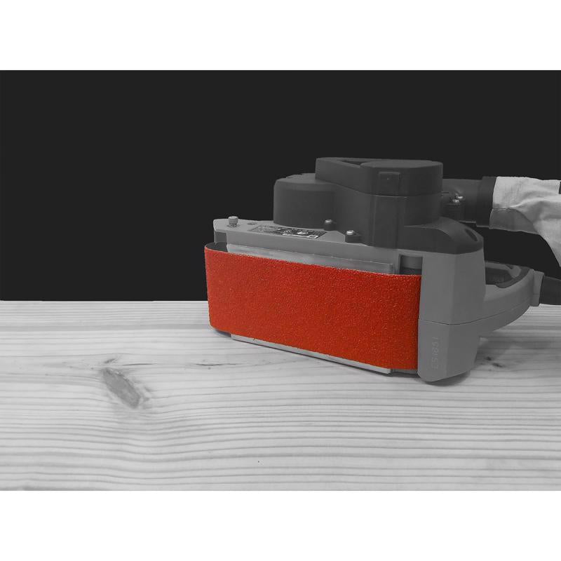 Sanding machine with a red sanding belt on a wooden surface