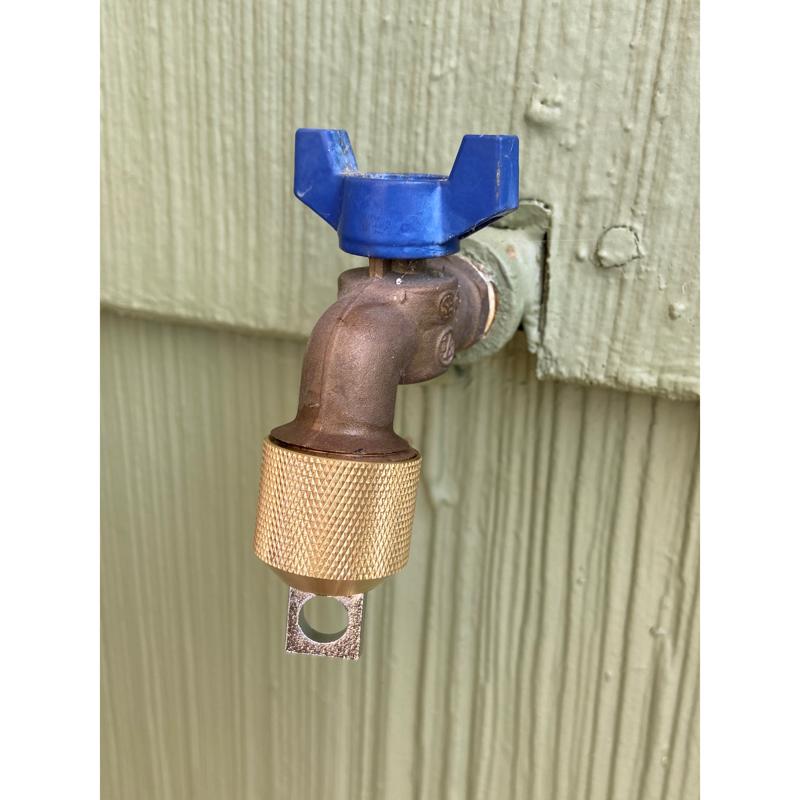 Metal garden faucet attached to a wooden wall