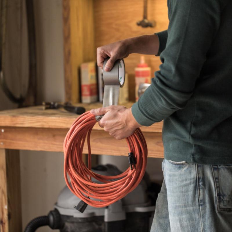 Duck Brand Gray Duct Tape being applied to an extension cord.