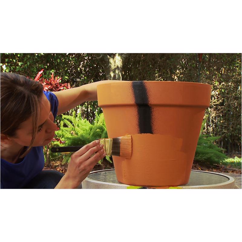 Person painting over Flex Seal that was used to fix a terracotta pot with a brush outdoors.