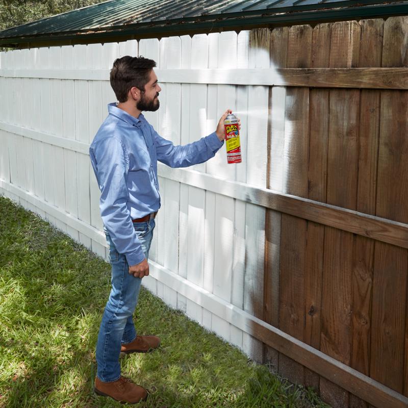 Man painting a wooden fence white Flex Seal Max.