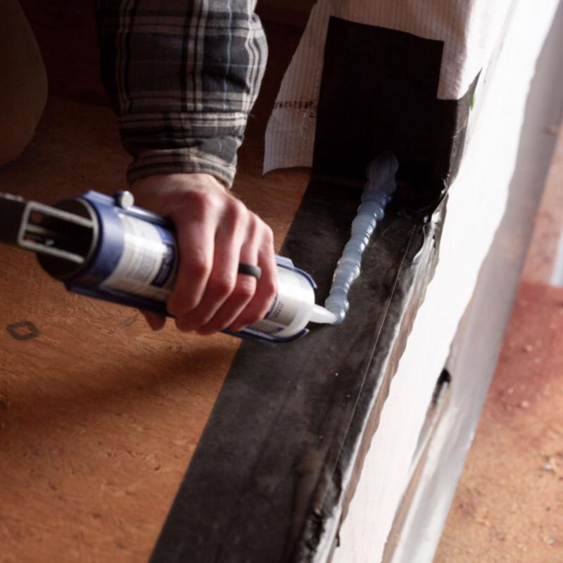 Person applying caulk to frog tape pro flashing tape using a caulking gun.