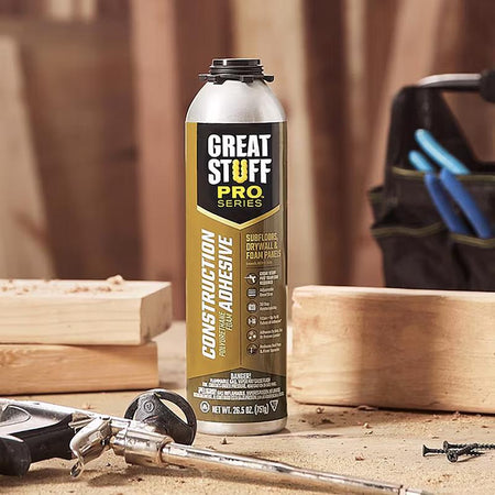 Great Stuff Pro Series construction adhesive can on a workbench with tools and wood.