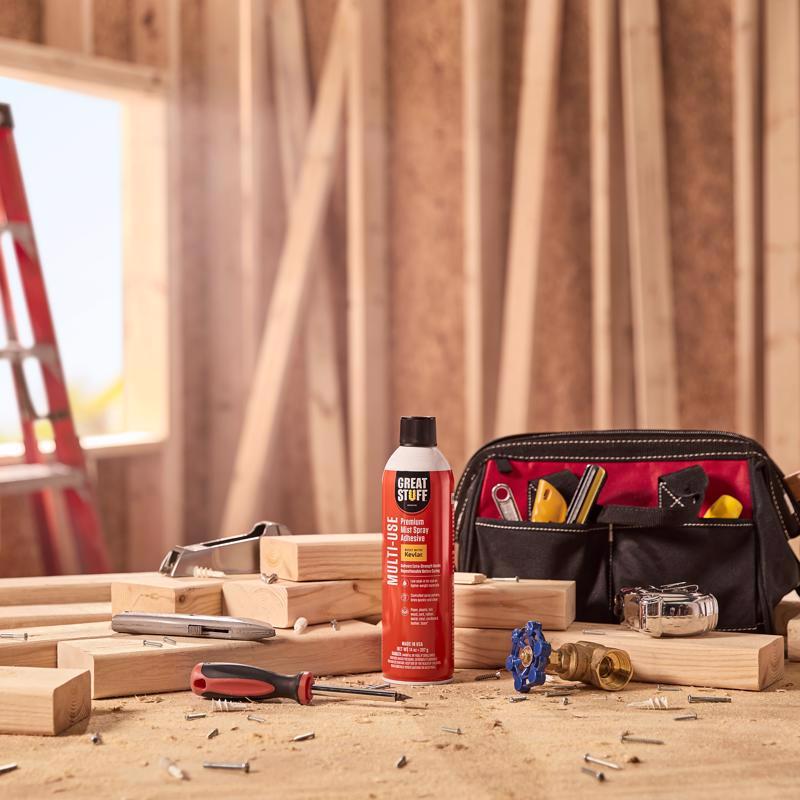 Great Stuff Multi-Use Premium Mist Spray Adhesive sitting on a table by wood and a tool pouch.