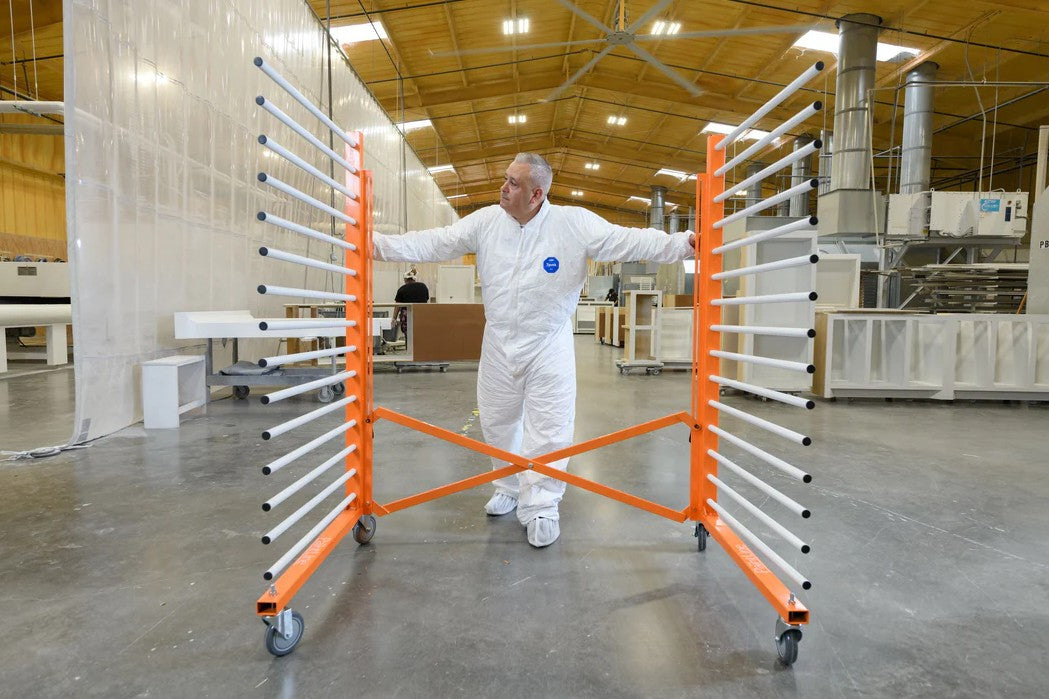 Person in a white protective suit standing between the PaintLine PDREX orange and silver racks in a warehouse.