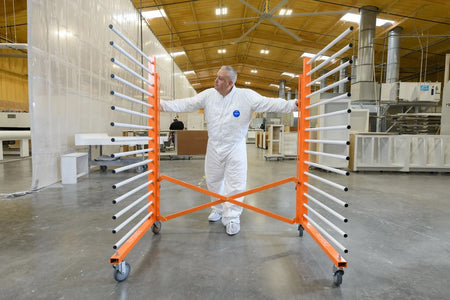 Person in a white protective suit standing between the PaintLine PDREX orange and silver racks in a warehouse.