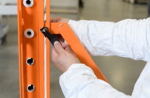 Person in white coat adjusting the PaintLine PDREX orange metal frame with a blurred background