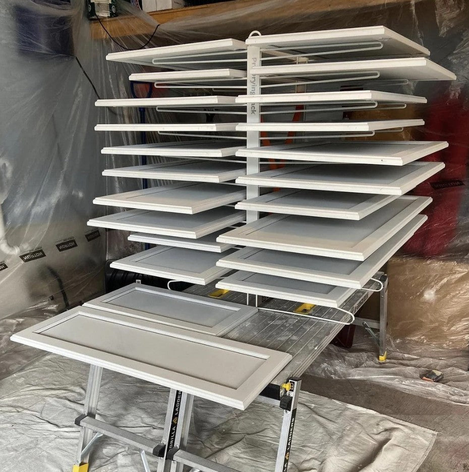 Stack of white cabinet doors on the PaintLine PDRTT Drying Rack with a blurred background