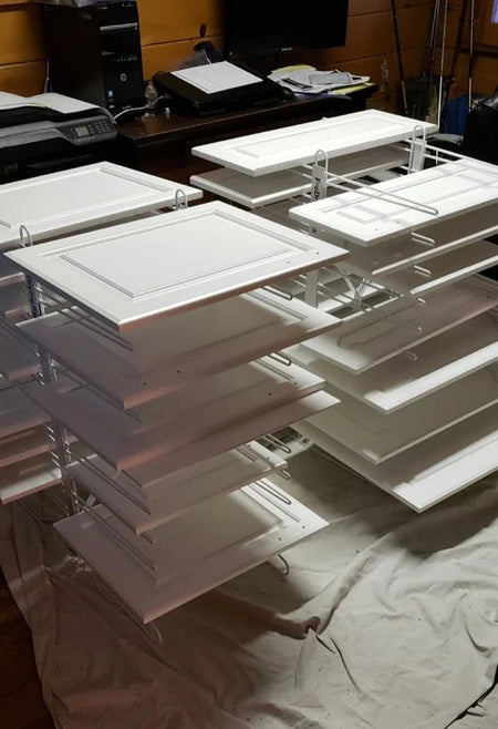 Two PaintLine PDRTT Drying racks holding white cabinet doors