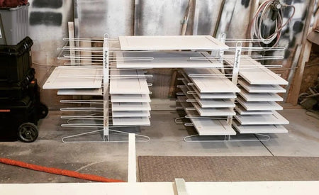 White cabinet doors on the PaintLine PDRTT drying racks in a garage type setting.
