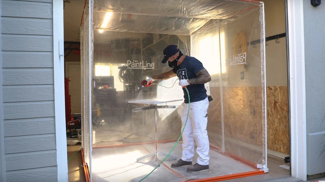 Person using the Paintline SPTY Spray Twirly Rotating Spray Table with a spray gun inside a paint booth with 'Paintline' branding.