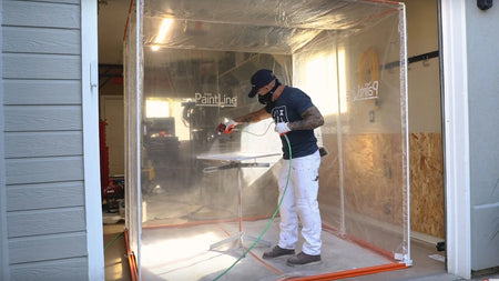 Person using the Paintline SPTY Spray Twirly Rotating Spray Table with a spray gun inside a paint booth with 'Paintline' branding.