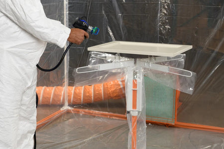Person in a white protective suit using a spray gun in a controlled spray booth using the PaintLine SPTYHD 
