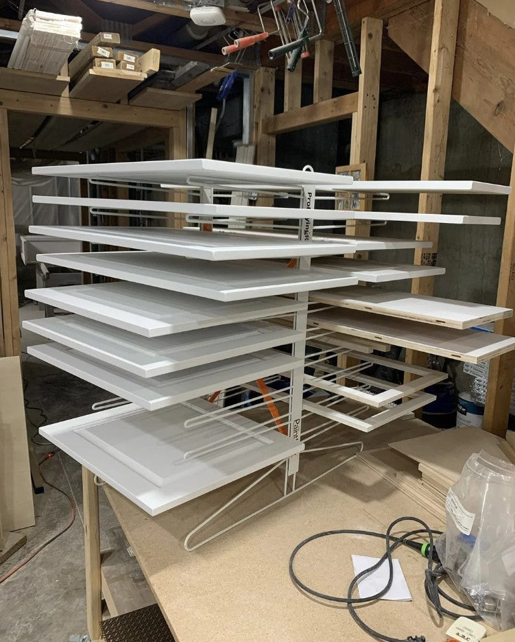 Stack of white sheets on the PaintLine IDRTT 20 Shelf Drying Rack in a workshop setting