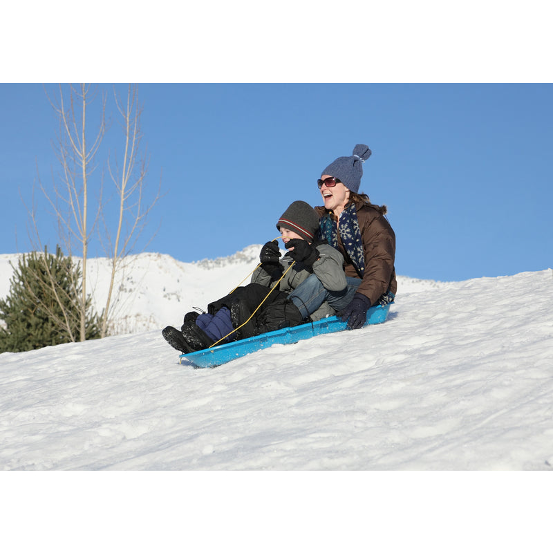 Two people sledding down a snowy hill on a clear day on the Winter Lightning Plastic Sled