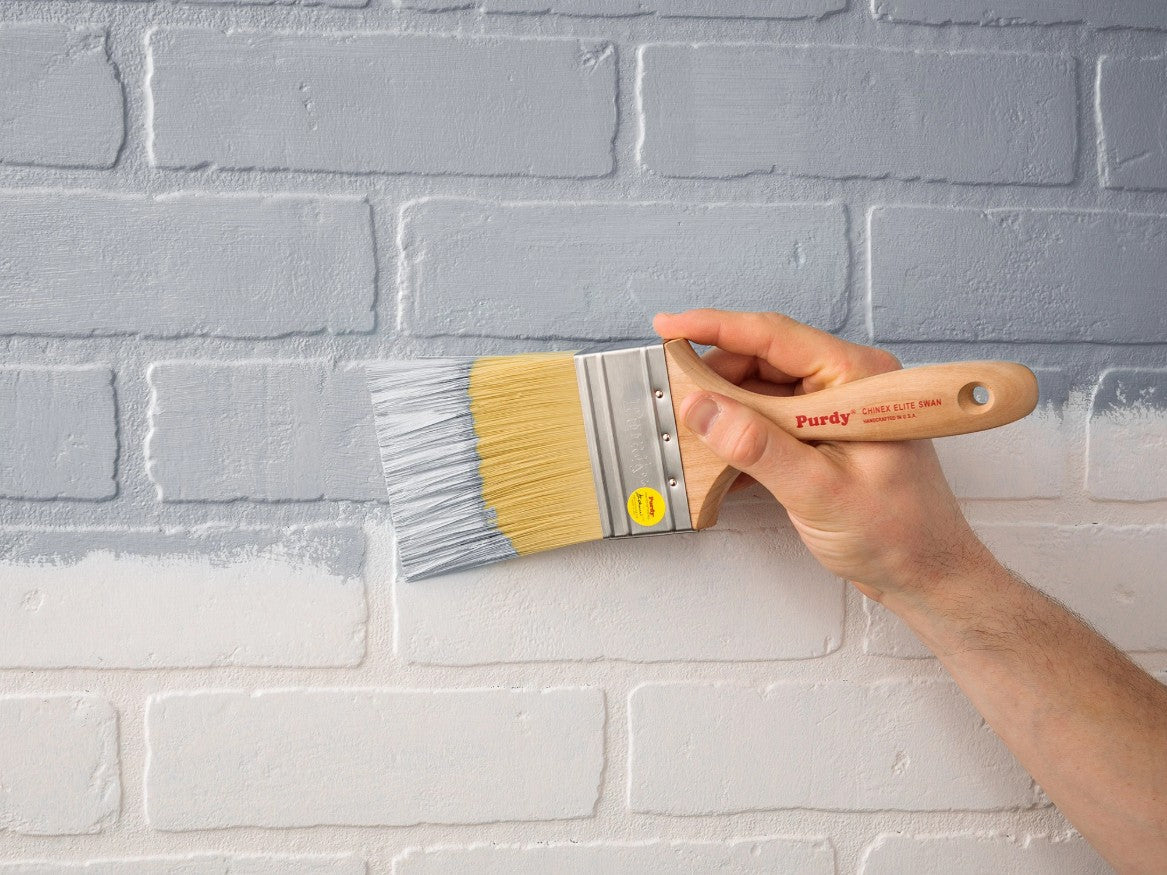 Man painting a brick wall with the Purdy Chinex Elite Swan paint brush.