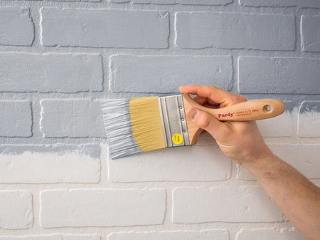 Man painting a brick wall with the Purdy Chinex Elite Swan paint brush.
